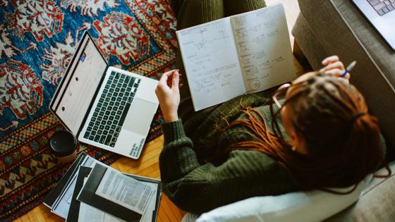Overhead view of a college student studying at home with a laptop and books