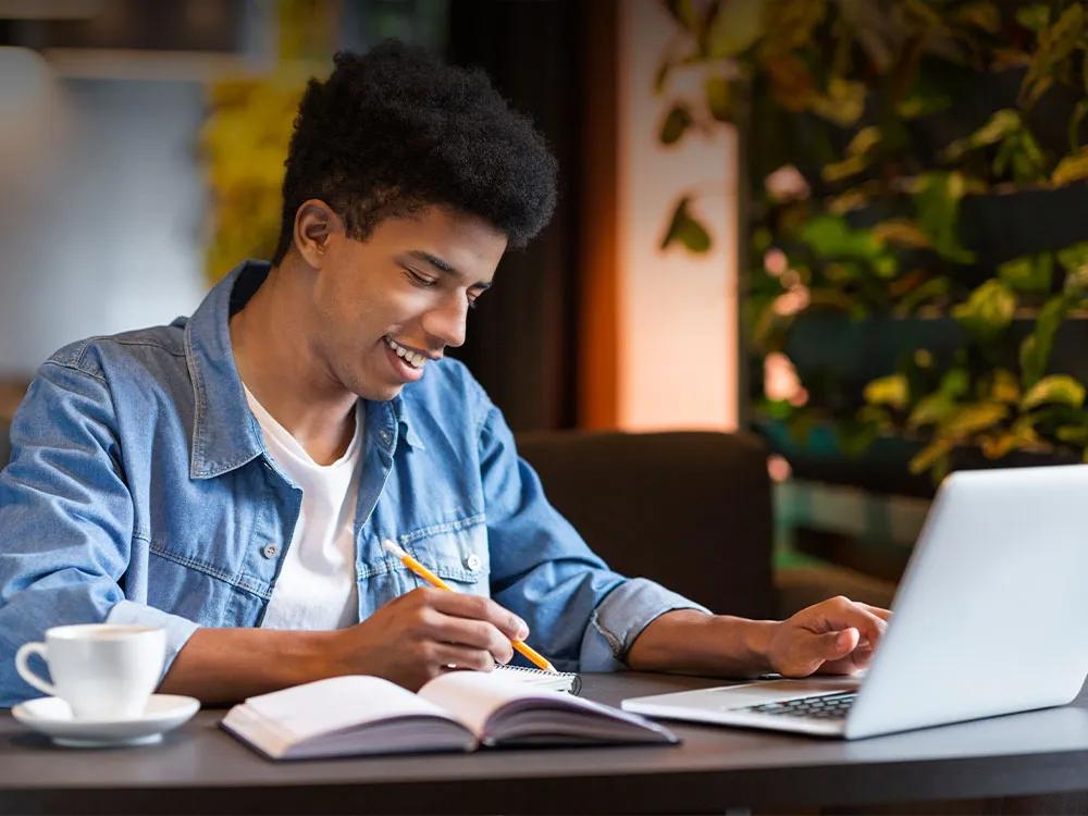 Young man looking down and studying on a laptop.