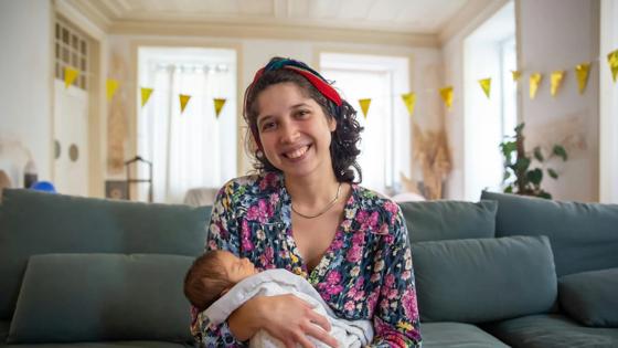 A mother holding her baby smiles as she considers her options as a returning student.
