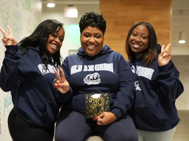 Celeste Harrell sits between her two daughters as they celebrate her graduation.