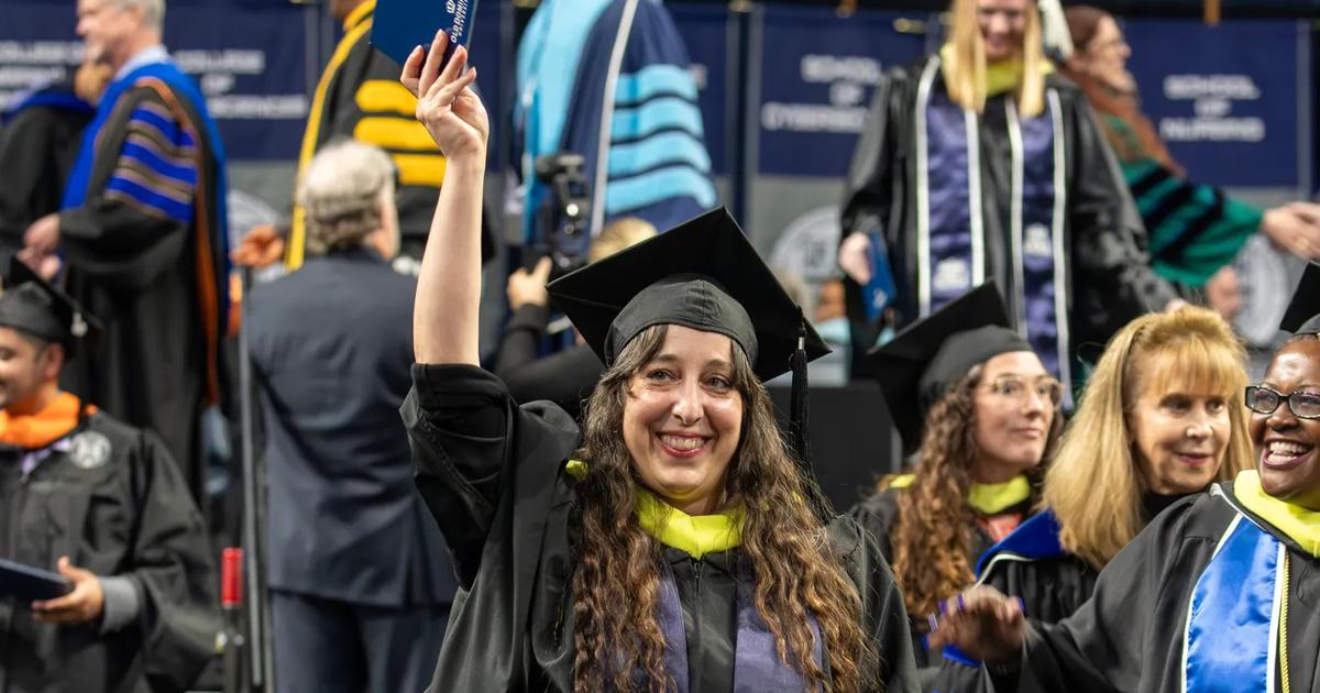 A graduating ODUGlobal student celebrates while walking in the Commencement ceremony.