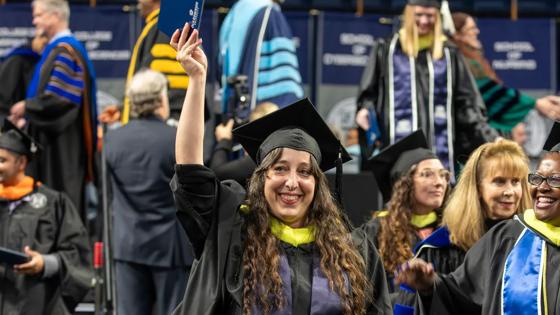 A graduating ODUGlobal student celebrates while walking in the Commencement ceremony.