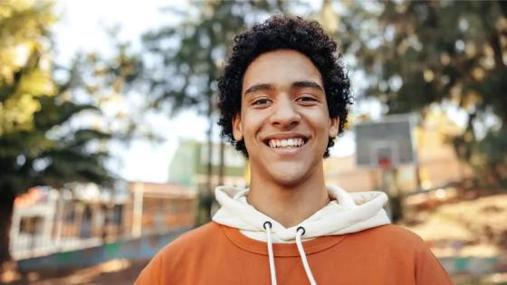 A smiling student is outside on a summer day