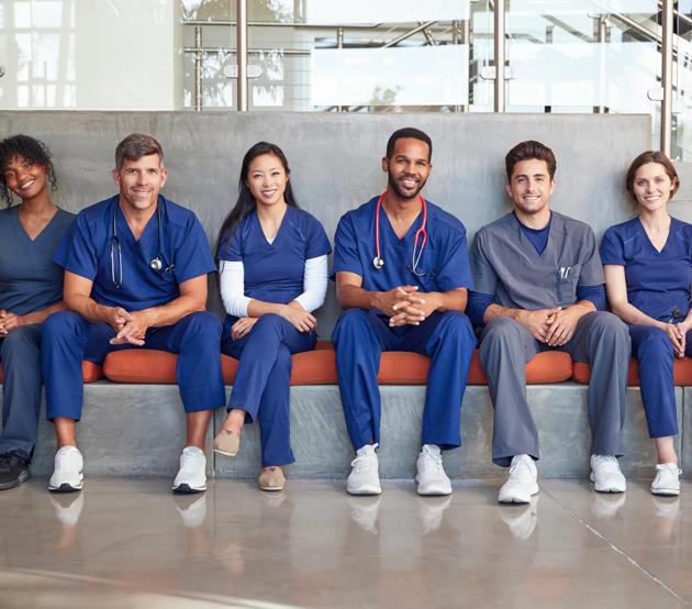 A diverse group of nurses taking a break from work, smiling at the camera in the hospital lobby.