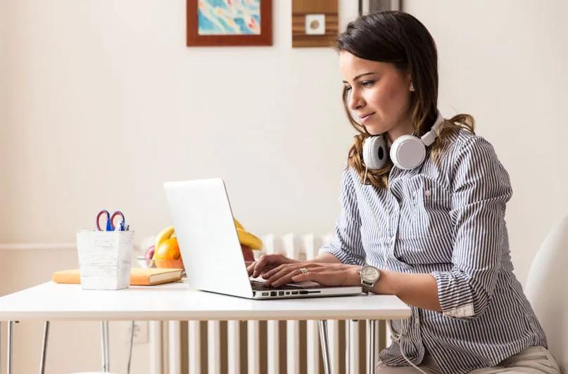 Student working on a laptop at home with headphones on.