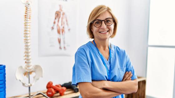 A kinesiology professional stands confidently in a clinical setting.
