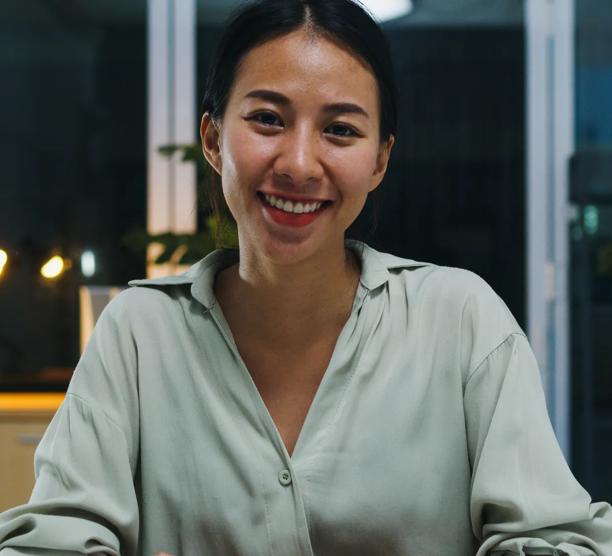 Portrait of beautiful executive businesswoman smart casual wear looking at camera and smiling, happy in modern office workplace night. Young Asia lady talk to colleague in video call meeting at home.