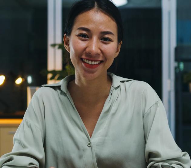 Portrait of beautiful executive businesswoman smart casual wear looking at camera and smiling, happy in modern office workplace night. Young Asia lady talk to colleague in video call meeting at home.