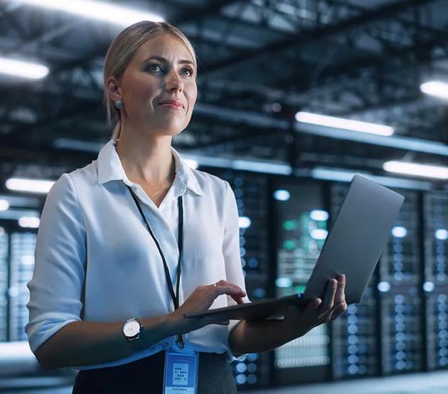 A data science professional stands holding a laptop