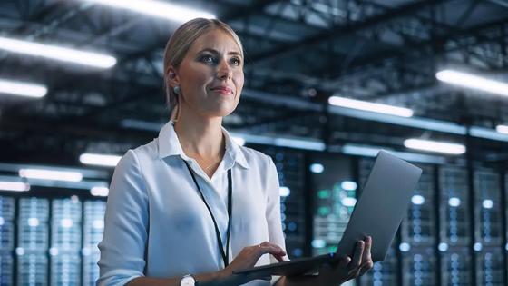 A data science professional stands holding a laptop