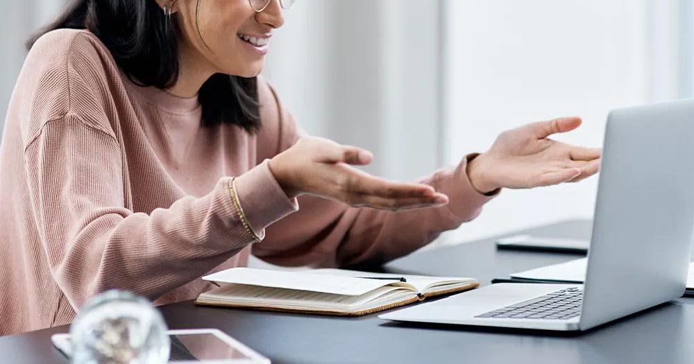 Woman speaking and gesturing during an online class on her laptop.