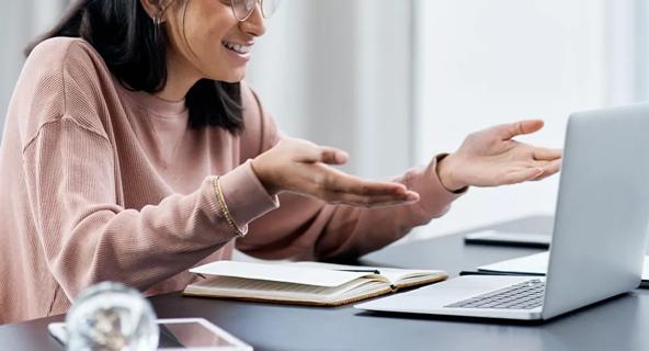 Woman speaking and gesturing during an online class on her laptop.