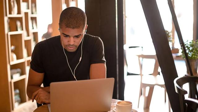 Man wearing earbuds and studying at laptop