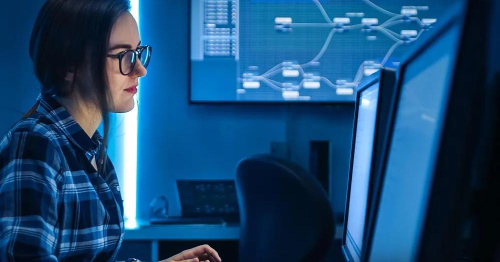 Person working at a computer with multiple monitors displaying network data.