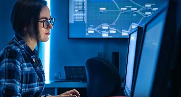 Person working at a computer with multiple monitors displaying network data.