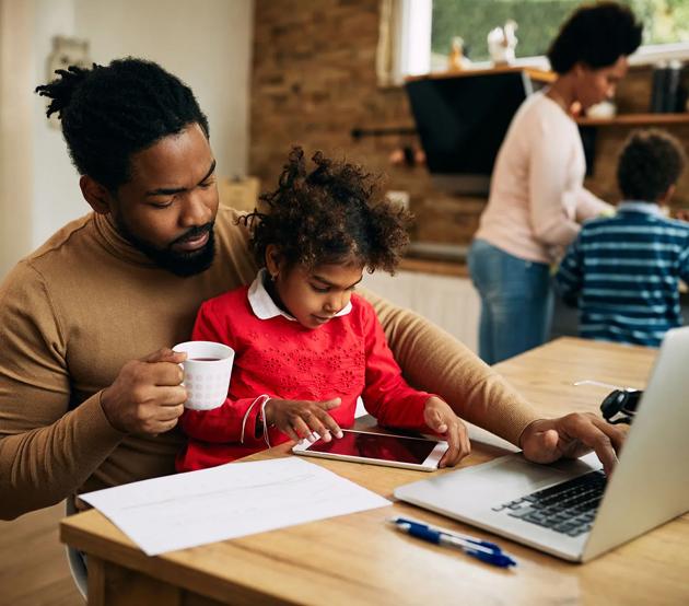 Dad working on laptop with child.