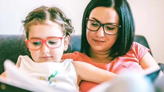 Child sitting on woman's lap and reading a book