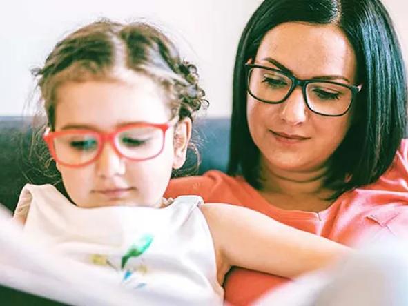 Child sitting on woman's lap and reading a book
