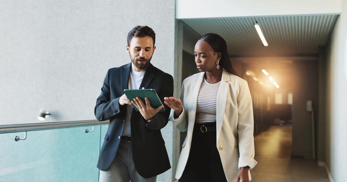 Business people walk with a digital tablet to discuss a meeting briefing.