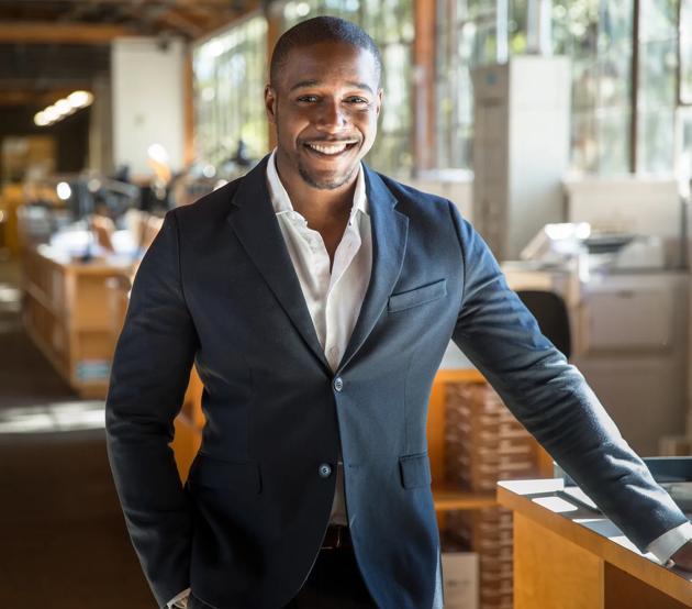 Handsome attractive african american modern professional smile standing confidently at the large interior workspace