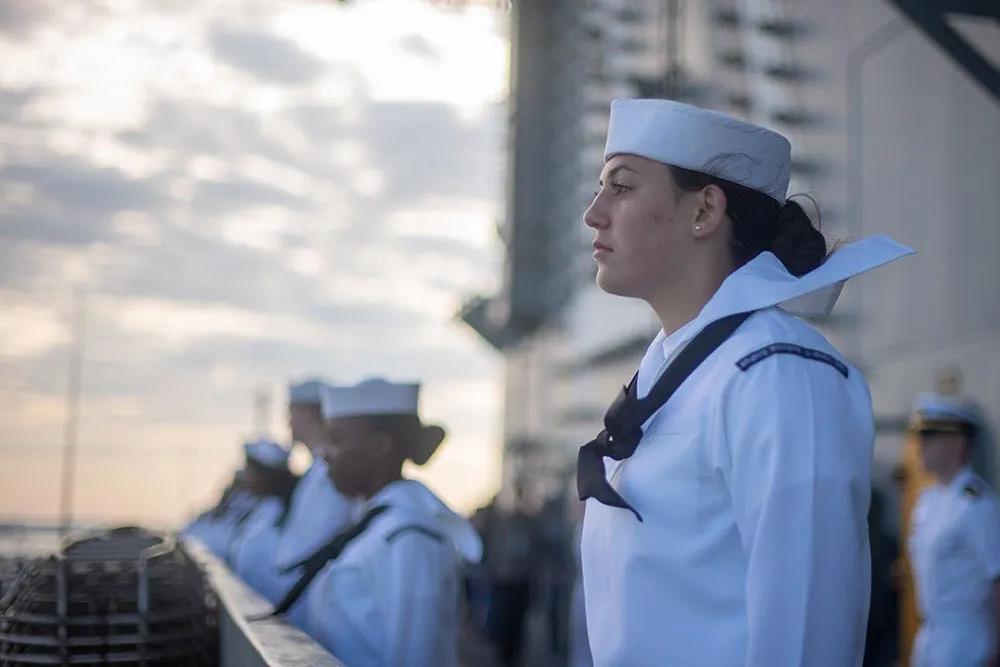 Female Navy service member in uniform looking ahead.