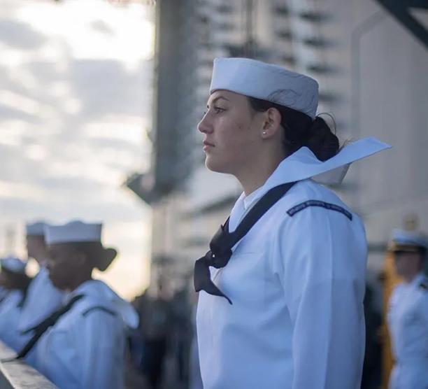 Sailor on the deck of a military ship pulling into port