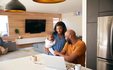 African American Family With Baby Daughter Using Laptop To Check Finances At Home