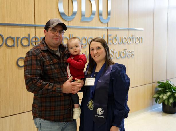 Emily Collins '25 (right) celebrates graduation with her husband and young daughter.