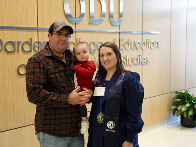 Emily Collins '25 (right) celebrates graduation with her husband and young daughter.
