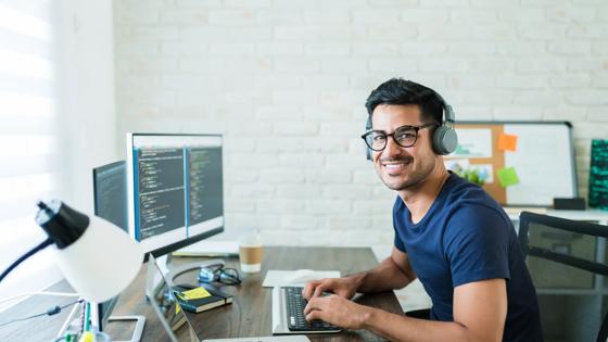 Male student coding at a desktop computer in a lab setting.