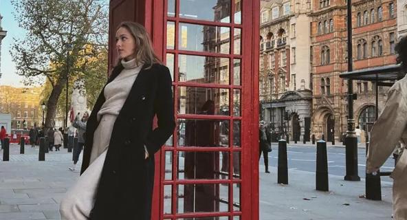 Zara Kelly, traveling through Europe while she earns her degree online, poses by a red phone booth in England.