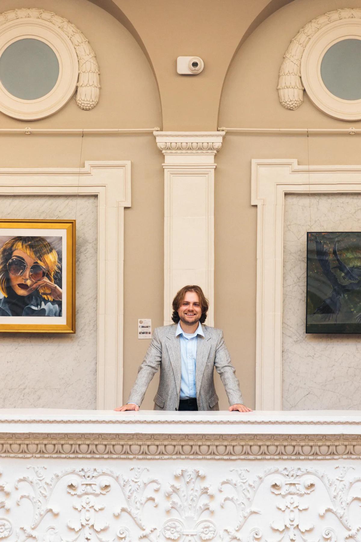 Student standing inside a campus building with artwork in the background.