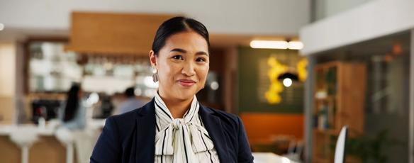 A hotel manager stands in a reception area holding a digital tablet for guest check in.