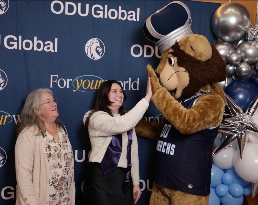Taylor Ripley gives a high-five to Big Blue, ODU's mascot, at the ODUGlobal graduation reception.