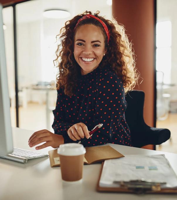 Woman working in accounting smiles at the camera while sitting at a computer.