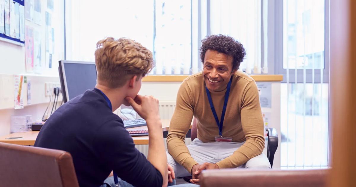 A college counselor and student chat about future plans as they sit in an office.