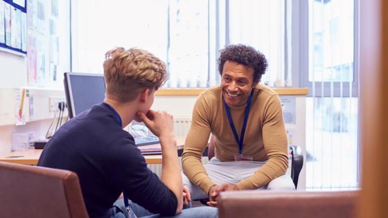 A college counselor and student chat about future plans as they sit in an office.