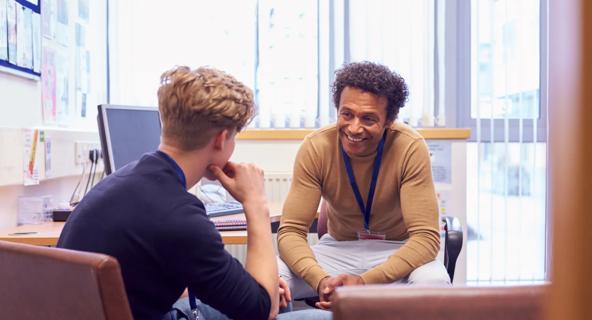 A college counselor and student chat about future plans as they sit in an office.