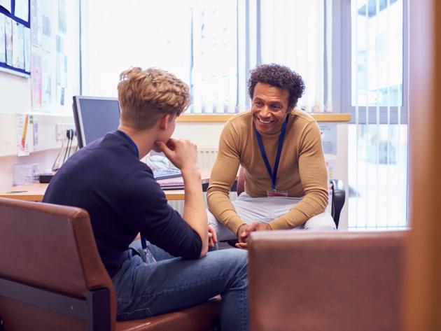 A college counselor and student chat about future plans as they sit in an office.
