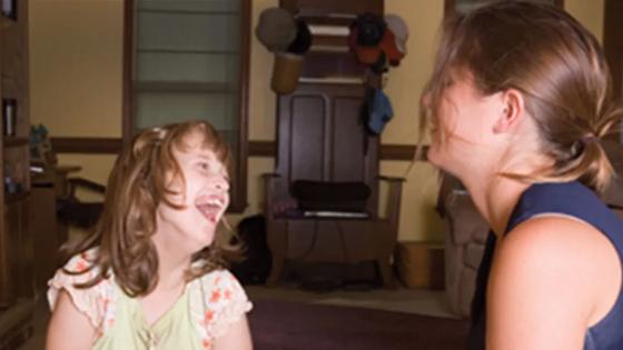 Woman smiling while studying on her laptop at home.