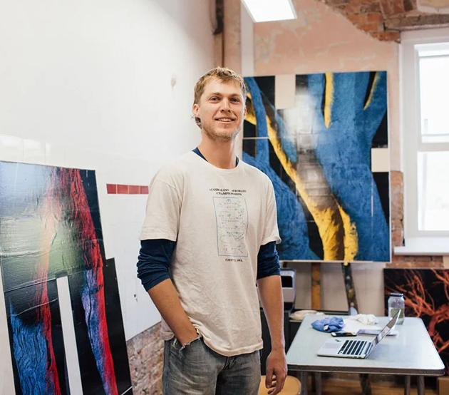 A transfer student stands confidently in his home studio, ready for the next stage in his education.