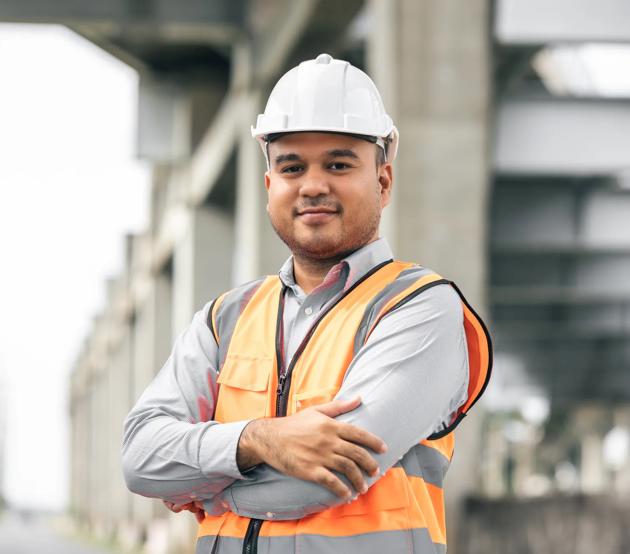 A construction engineer stands confidently at the worksite.