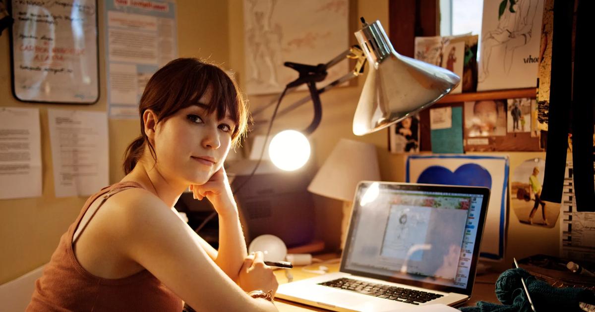 Portrait of woman sitting with laptop computer at table in home