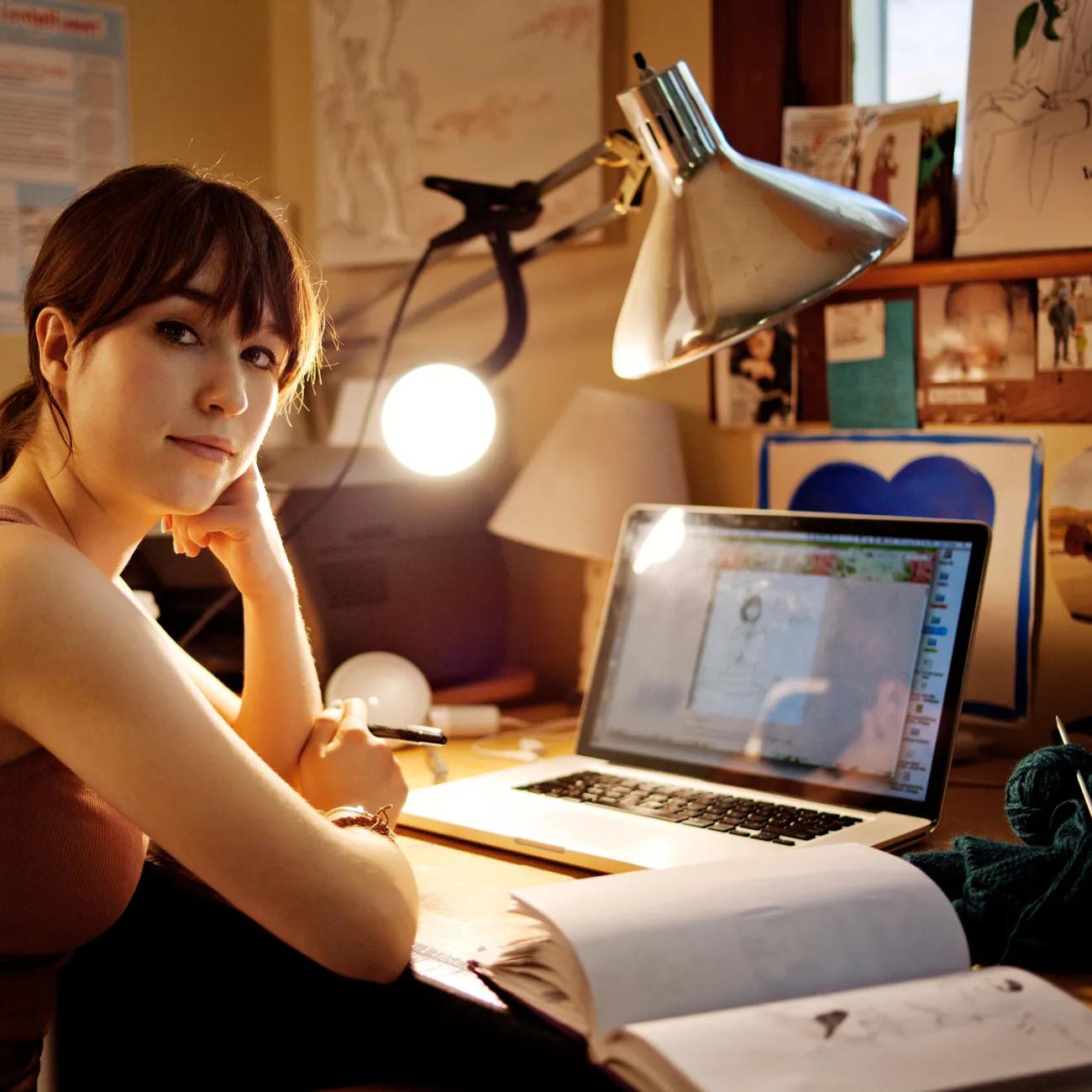 Portrait of woman sitting with laptop computer at table in home
