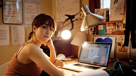 Portrait of woman sitting with laptop computer at table in home