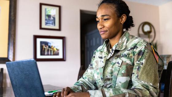 Service member in uniform working on a laptop.