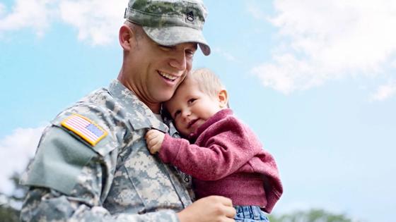 Military service member holds his child while in uniform