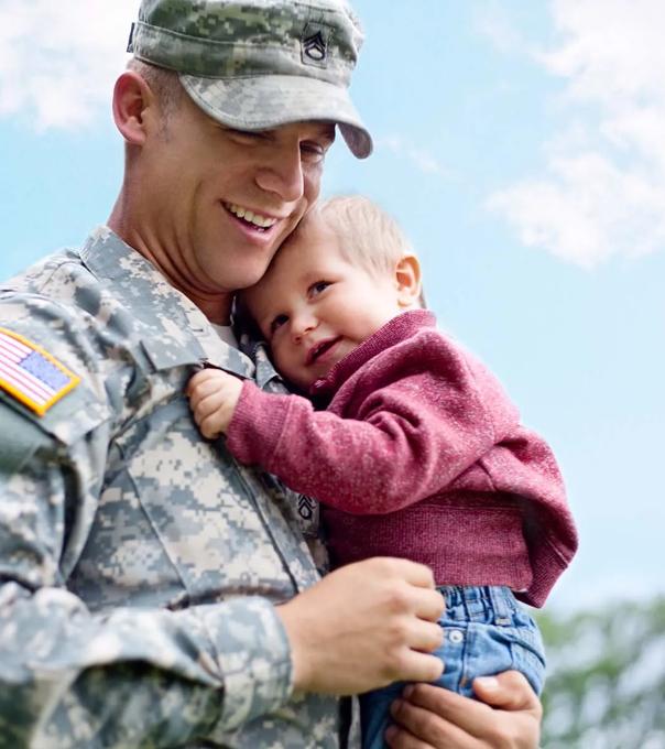 Military service member holds his child while in uniform