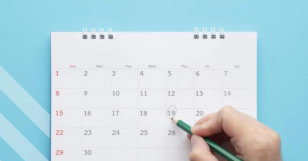Hand circling a date on a monthly calendar to mark an important academic deadline.