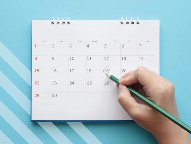 Calendar on blue background with hand recording a comment on a date